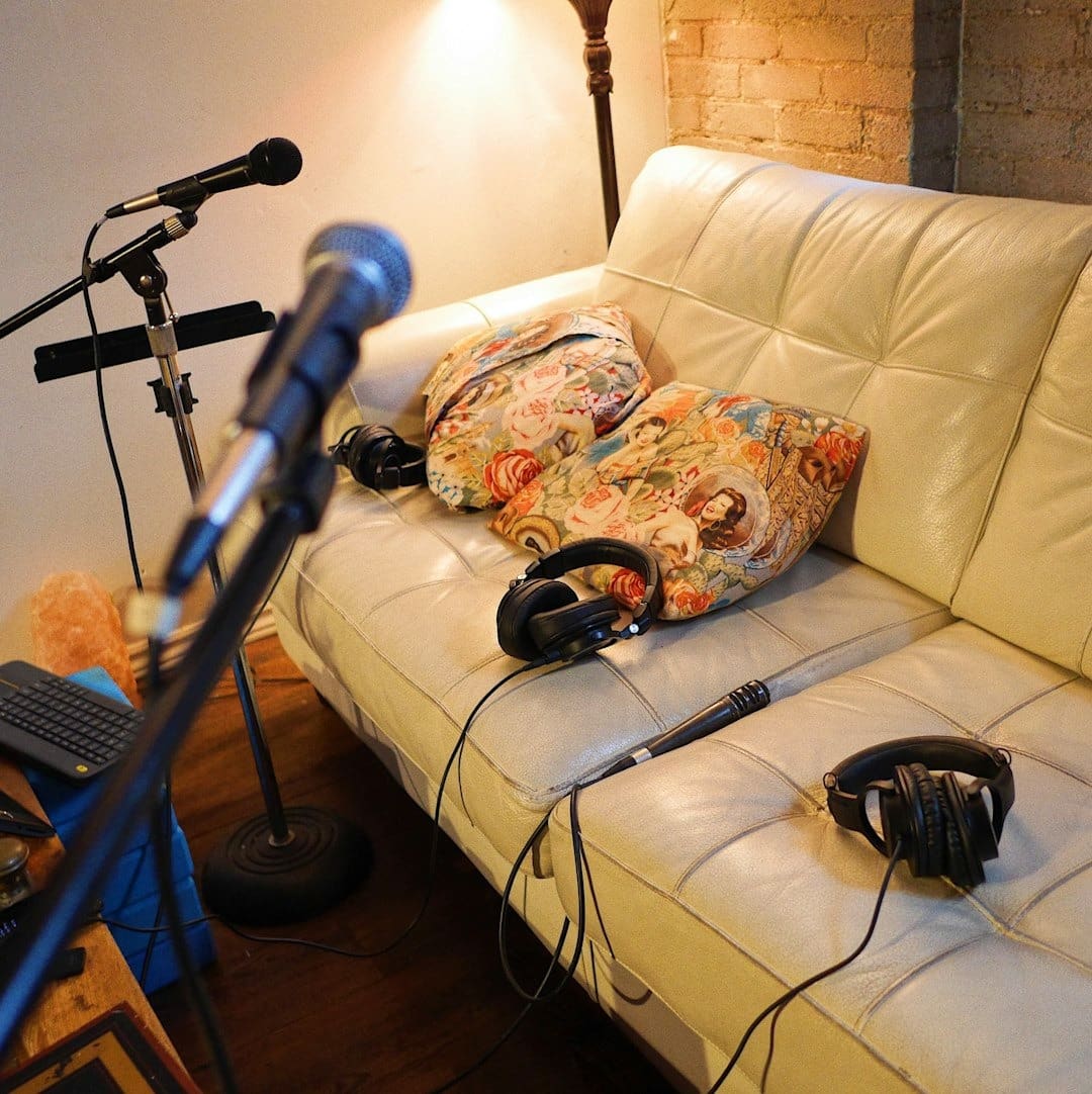 Microphones and headphones arranged around a couch in a studio.
